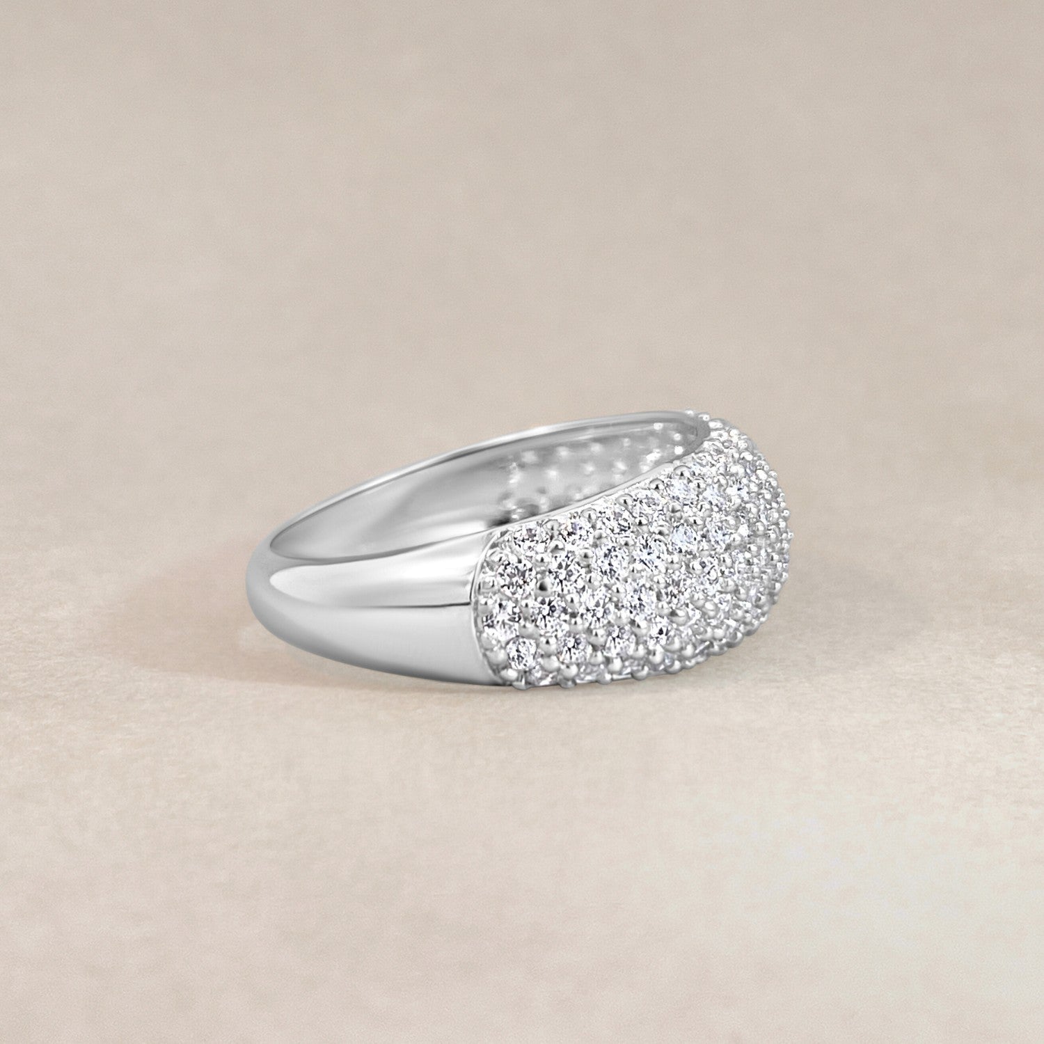 Silver ring with crystal accents on a beige background